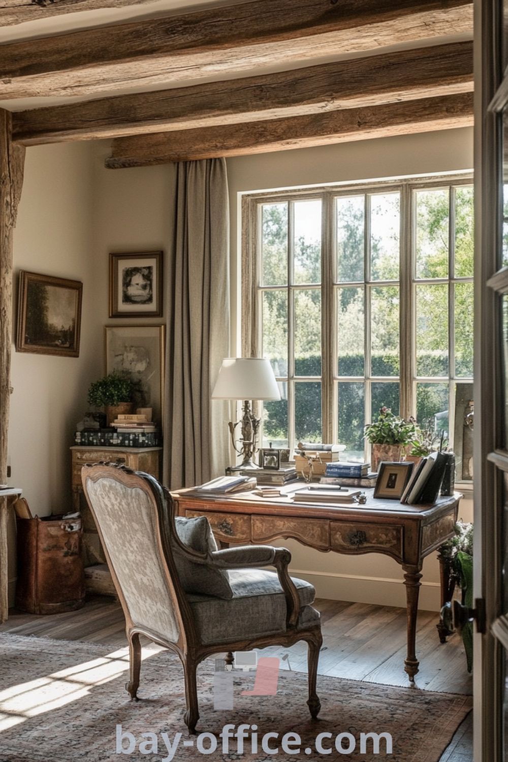 Elegant French country home office featuring rustic wooden beams, an antique desk, vintage armchair, and natural light, creating a cozy aesthetic perfect for inspiration and productivity. For more design tips and ideas that will inspire productivity, visit bay-office.com.