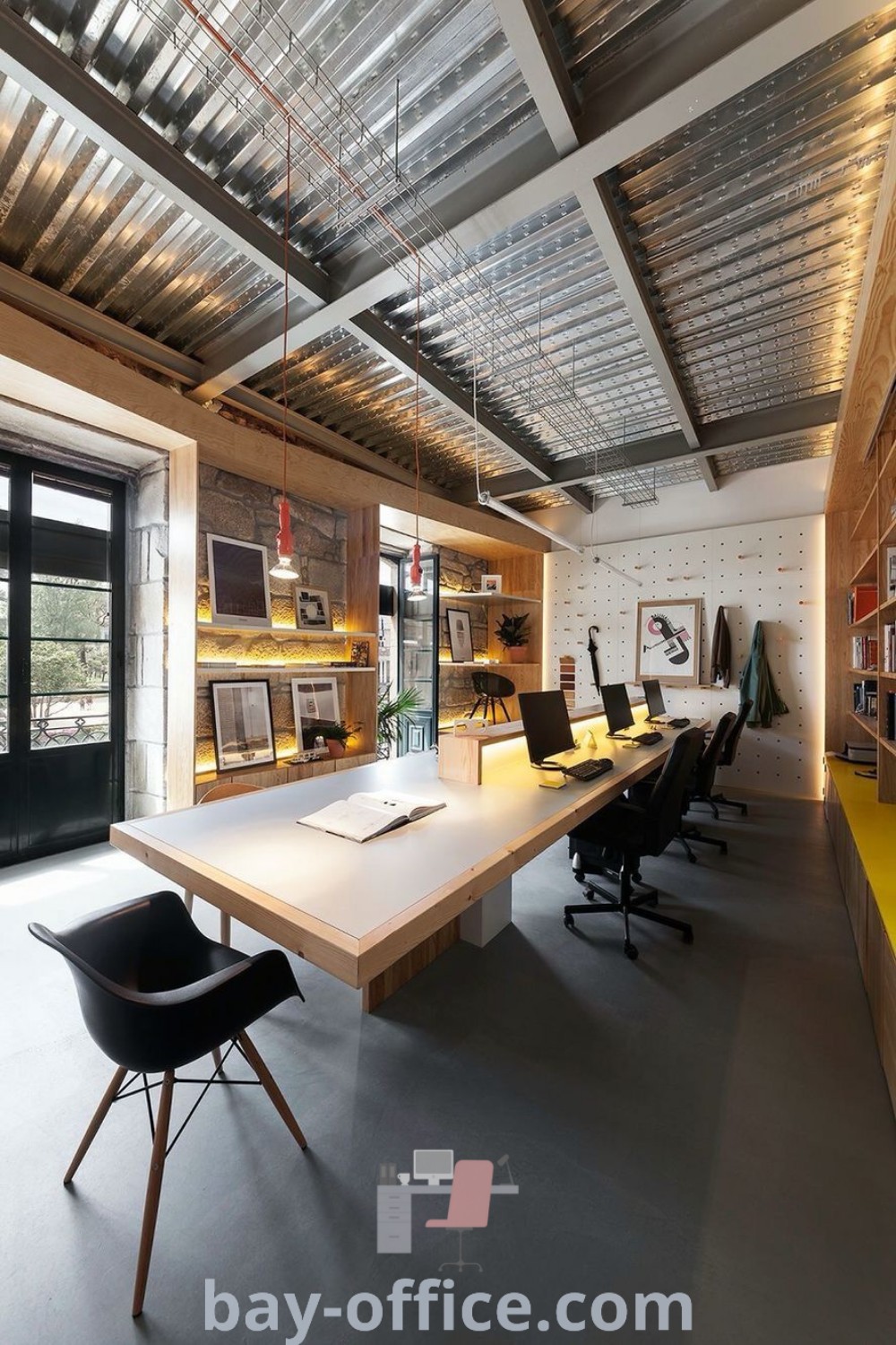 Factory office featuring a long central table, chairs, and bookshelves for an inspiring industrial office design. Perfect for boosting productivity and creating a cozy aesthetic in your workspace. Explore more office layout ideas and design trends at bay-office.com.
