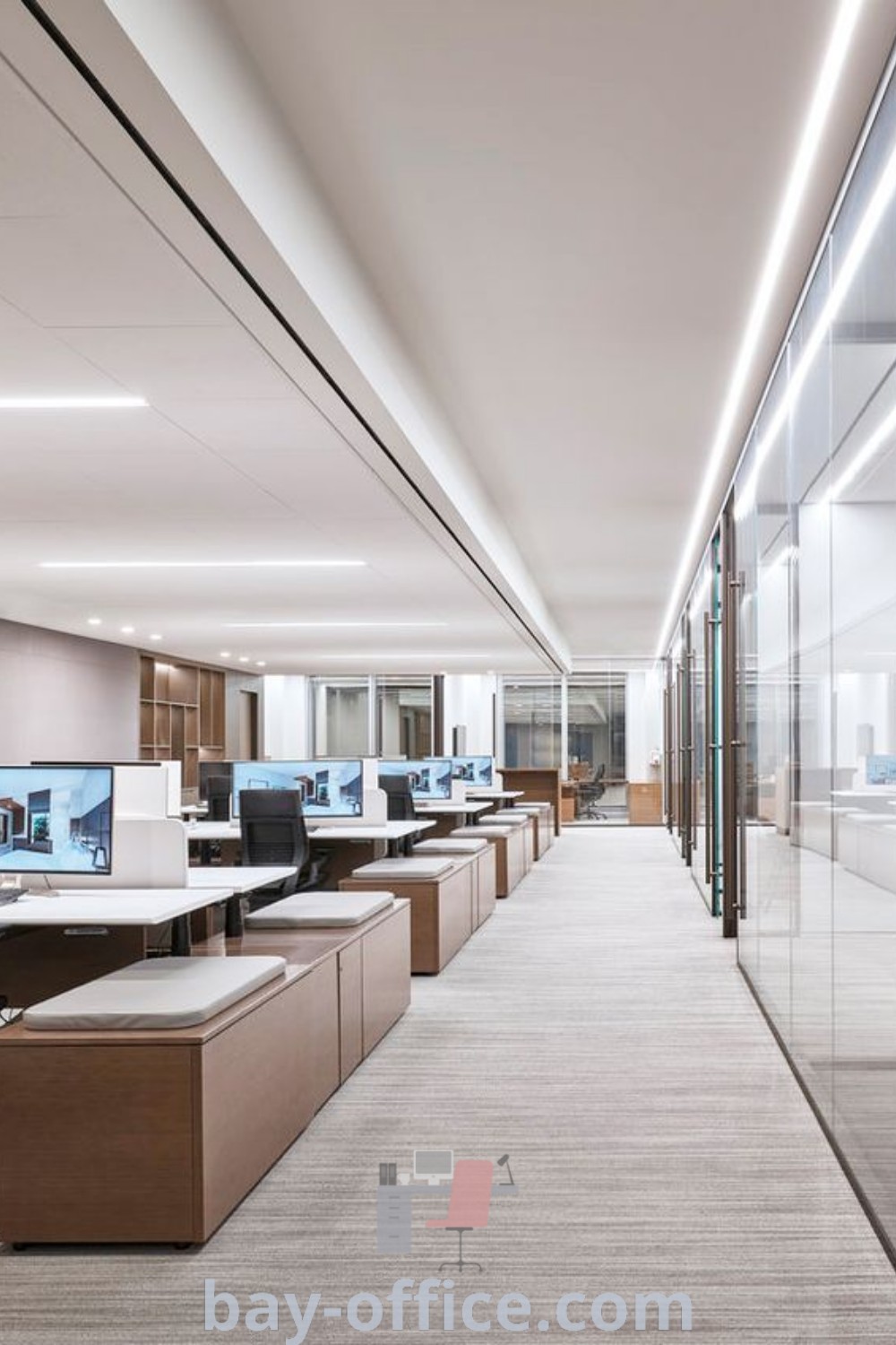 Modern office interior featuring contemporary open design with rows of desks and computer screens, highlighted by glass walls. Explore inspiring office building interior design trends at bay-office.com.