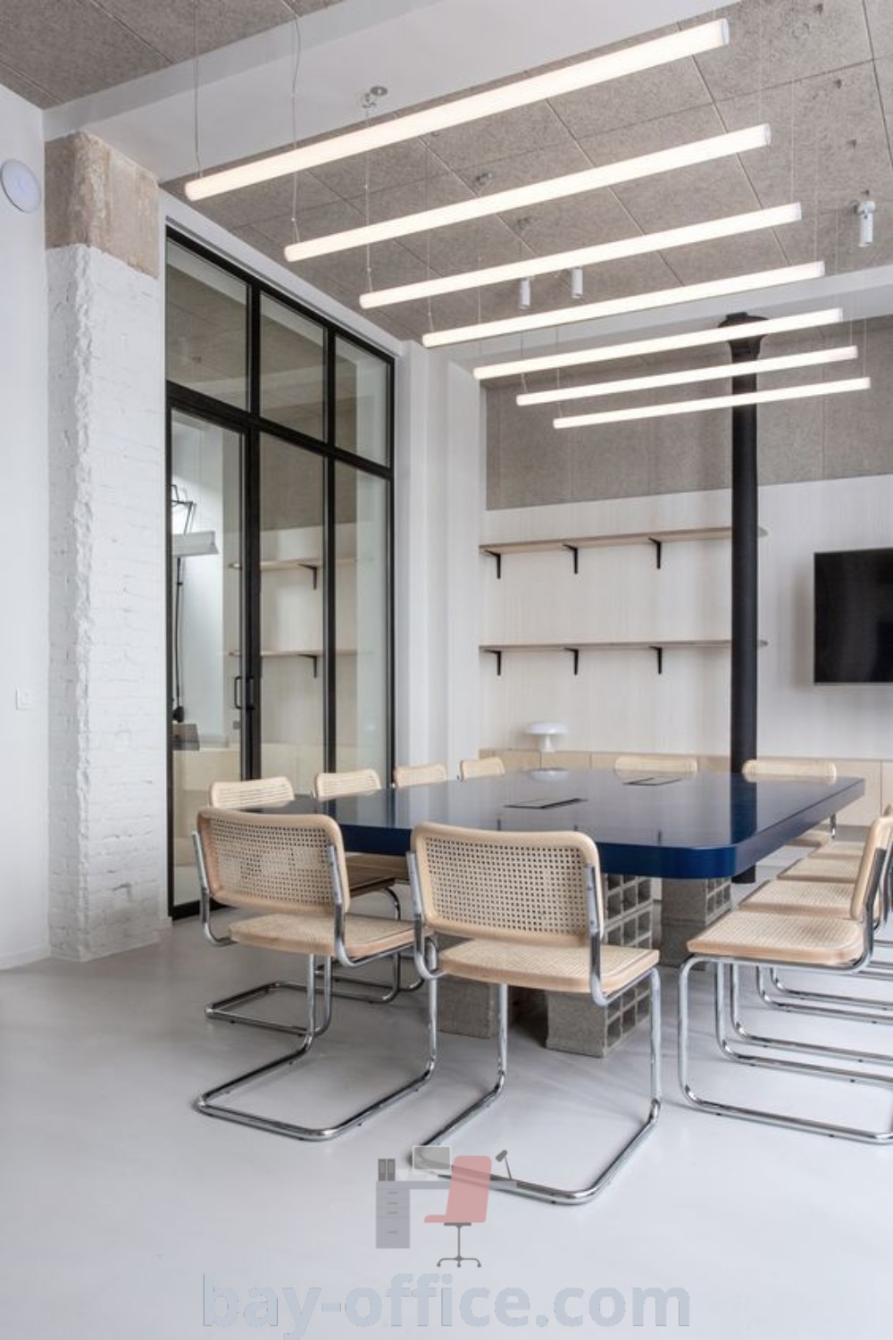 A modern minimal office design featuring a table with chairs and a wall-mounted television, showcasing ideas that inspire productivity and cozy aesthetics. Discover functional office decor ideas and trends at bay-office.com.