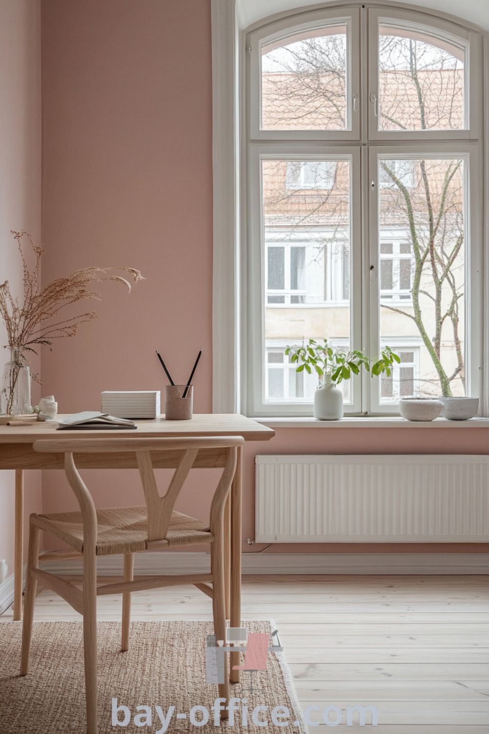Scandinavian home office featuring soft pink walls, light wooden furniture, and a spacious window, creating a cozy aesthetic perfect for enhancing productivity and reflection. Explore more design tips and ideas at bay-office.com.