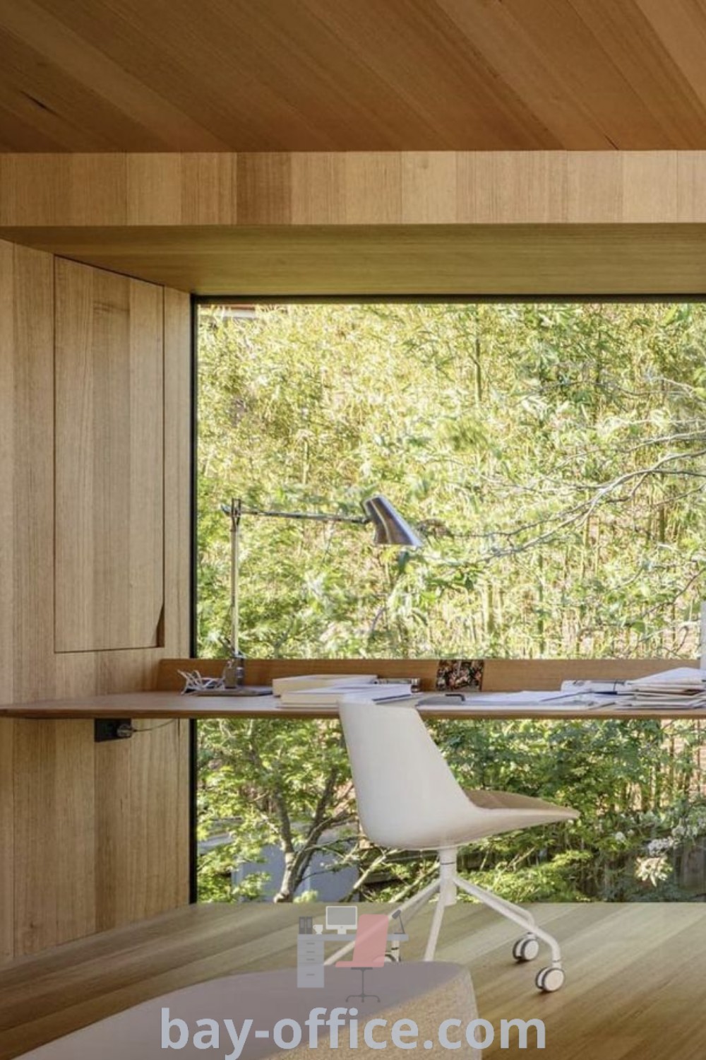 Cozy home office in the woods with a desk and chair by a large window, showcasing greige paint colors. Discover ideas that inspire productivity and enhance your work-from-home setup at bay-office.com.