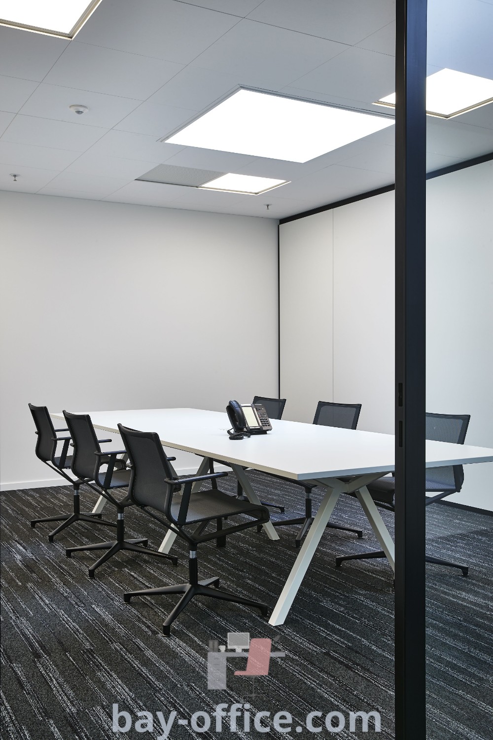 White conference room with black chairs, designed for effective meetings and brainstorming. Aesthetic features and functional elements make it a perfect choice for office spaces. Discover inspiring meeting room design ideas at bay-office.com.